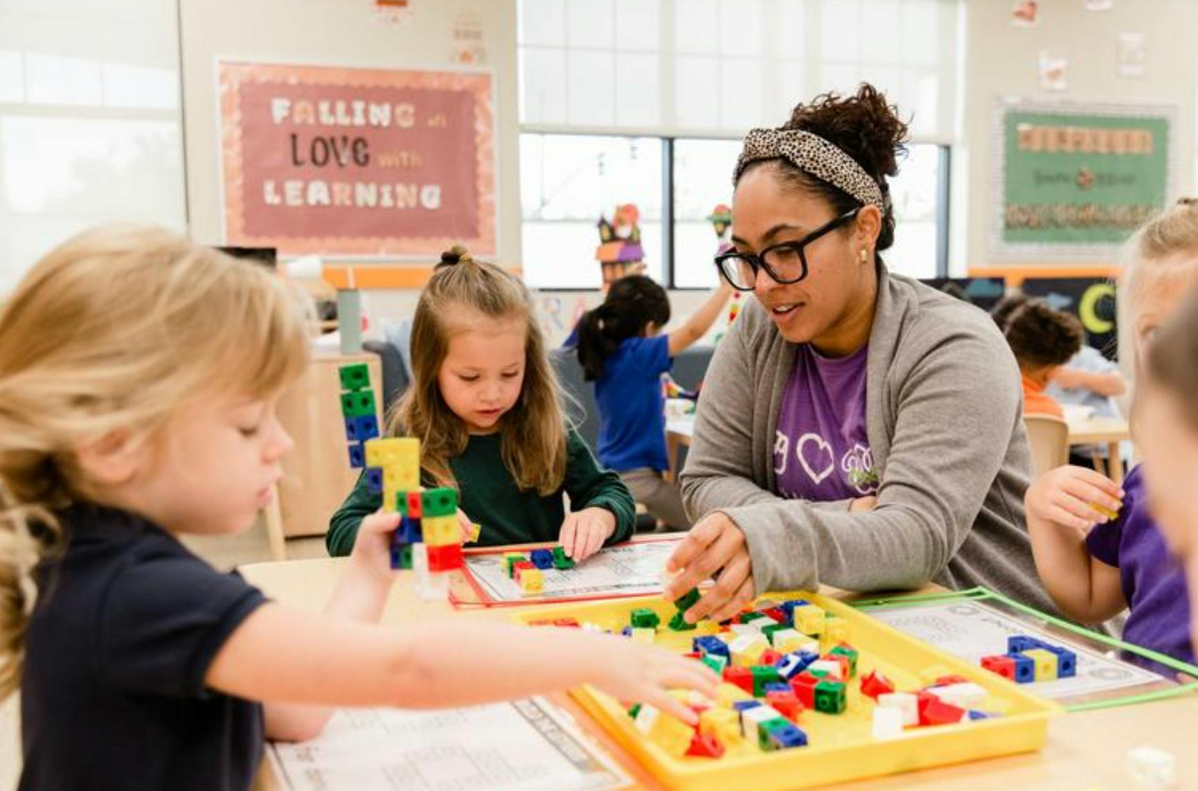 Adult and children playing with colorful building blocks in a classroom