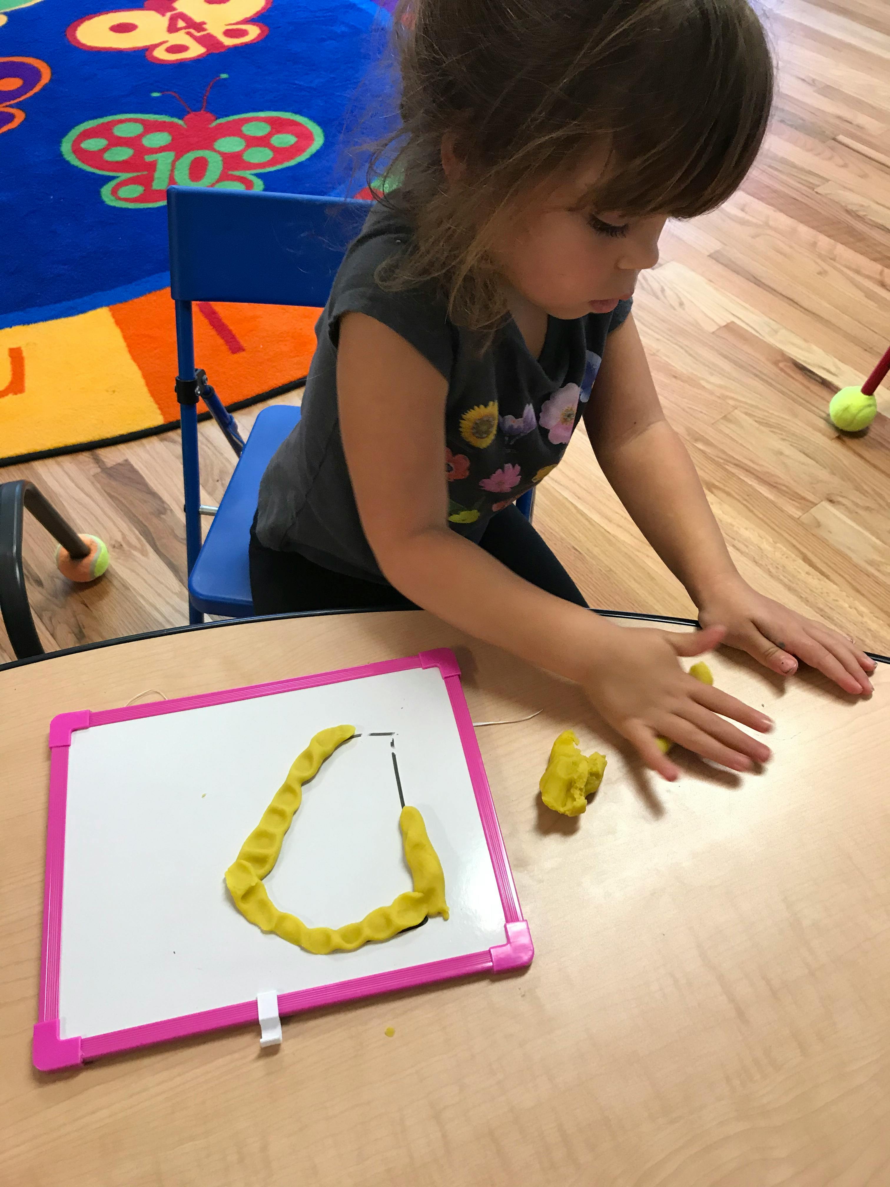 Child playing with yellow playdough on a table