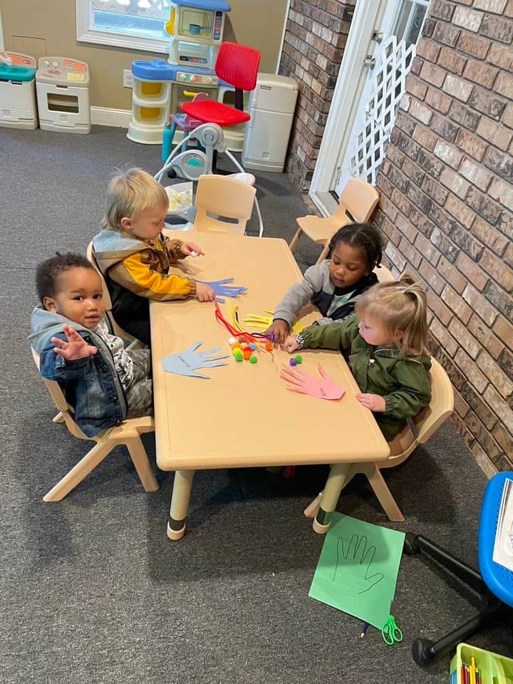Four children sitting at a table doing crafts