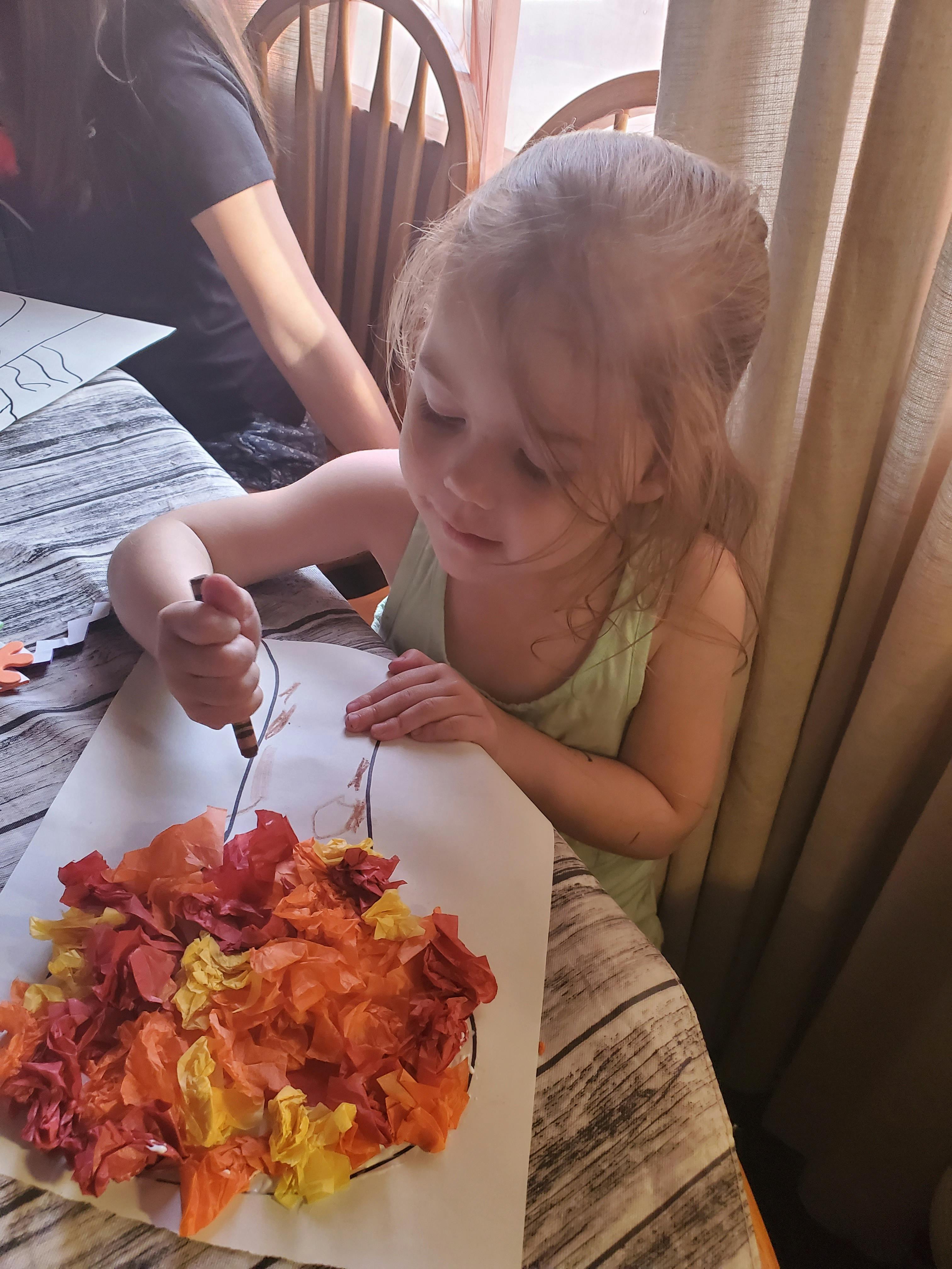 Child drawing on paper with colorful tissue paper art