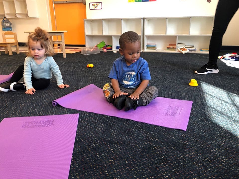 Two children sitting on purple yoga mats