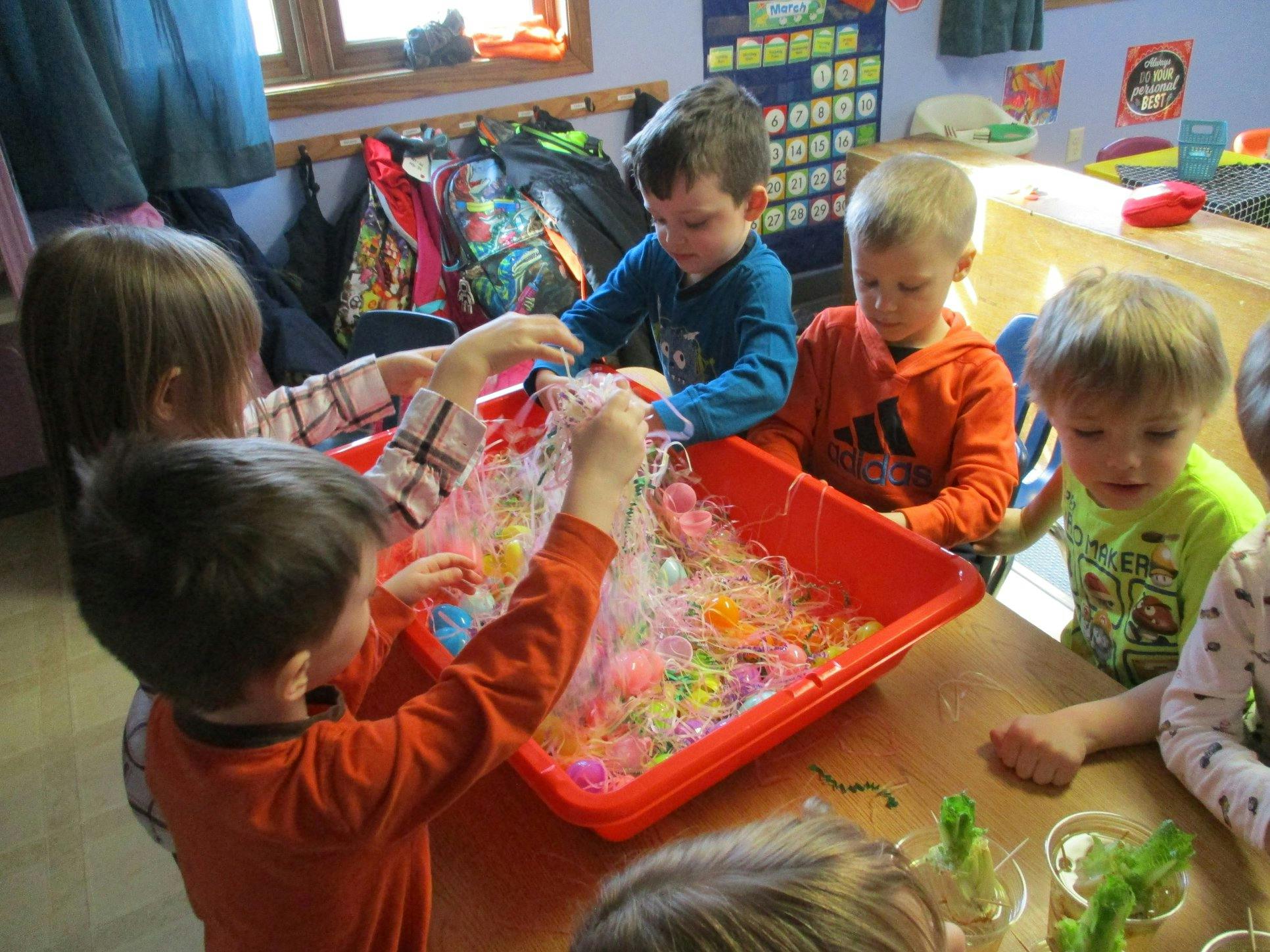 Children playing with colorful beads in a red bin