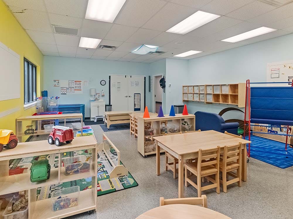 A colorful classroom with tables, chairs, shelving units, and toys