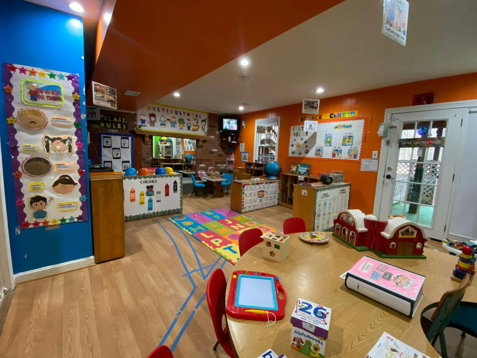 Children's classroom with bright orange walls and various learning stations
