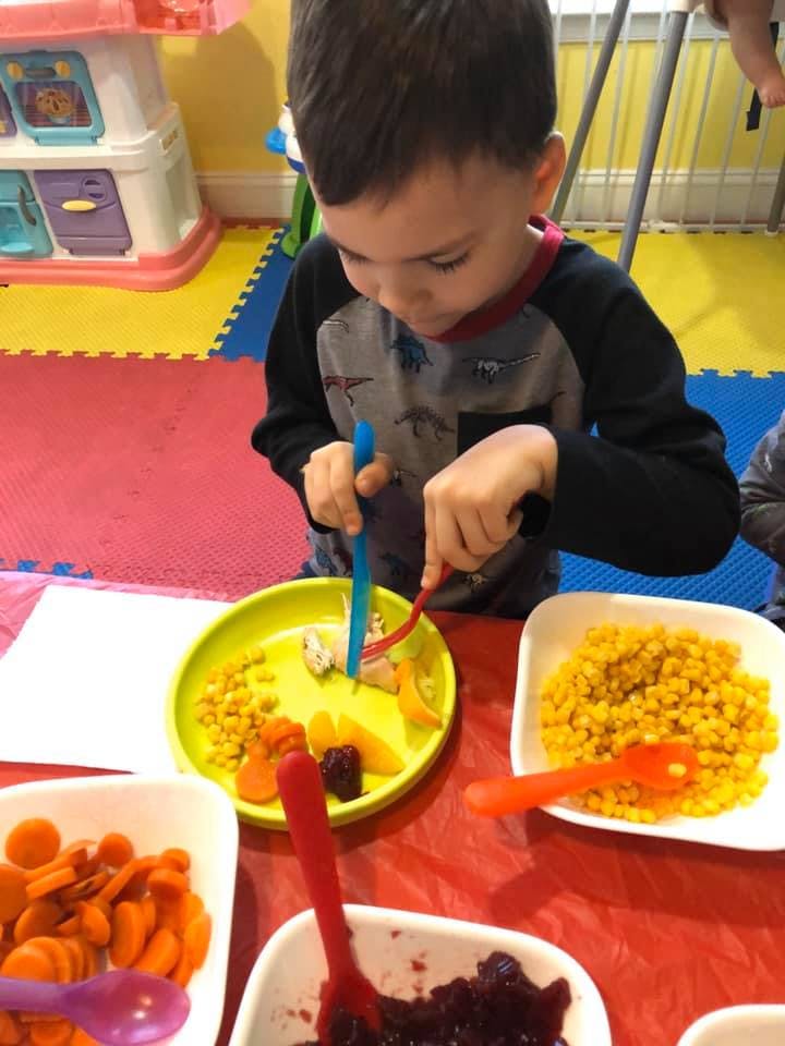 Child using utensils to eat food from a plate