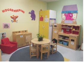 Playroom with small table and chairs, toy kitchen, and red armchair