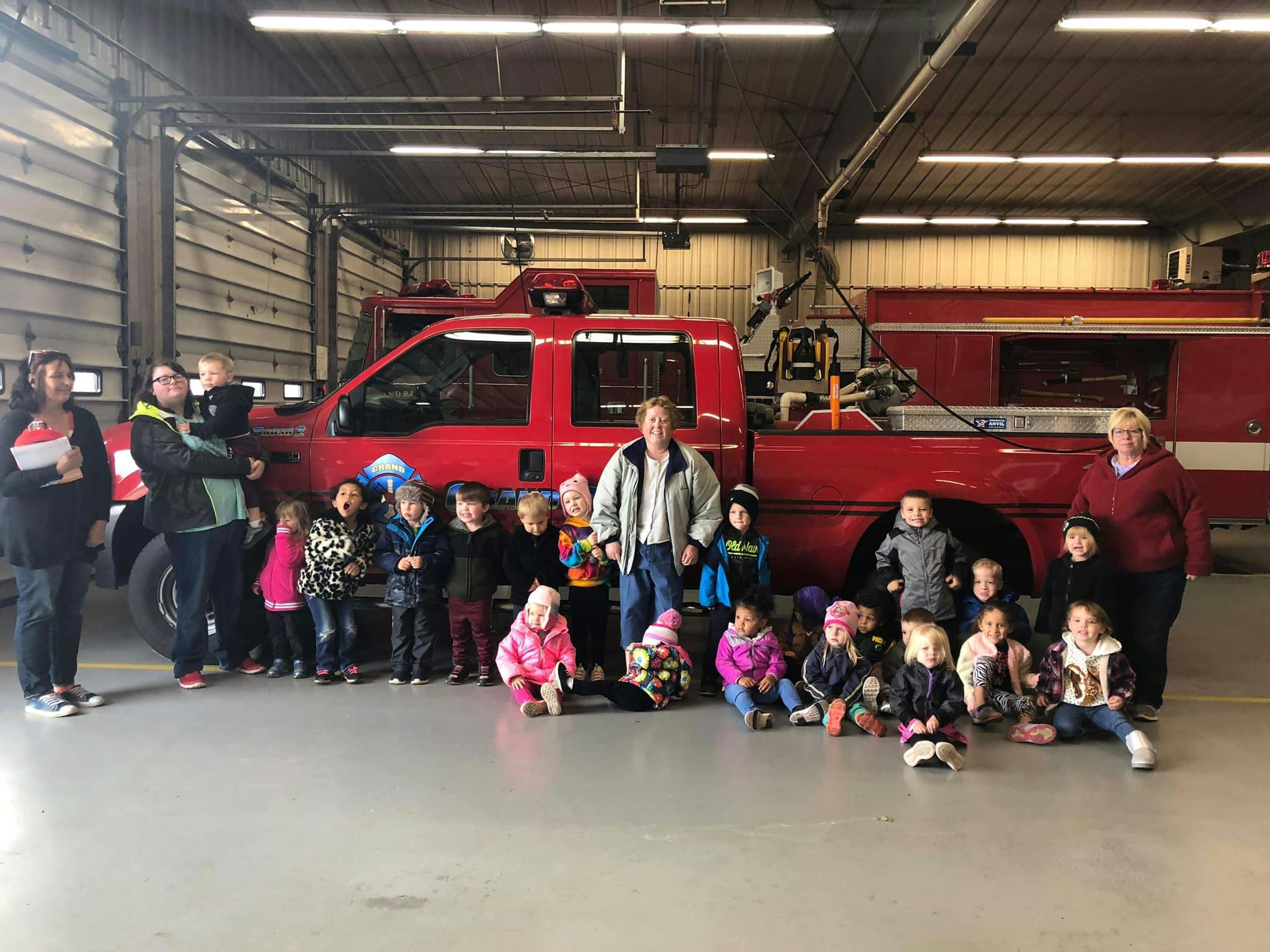 Adults and children posing in front of a red fire truck in a garage