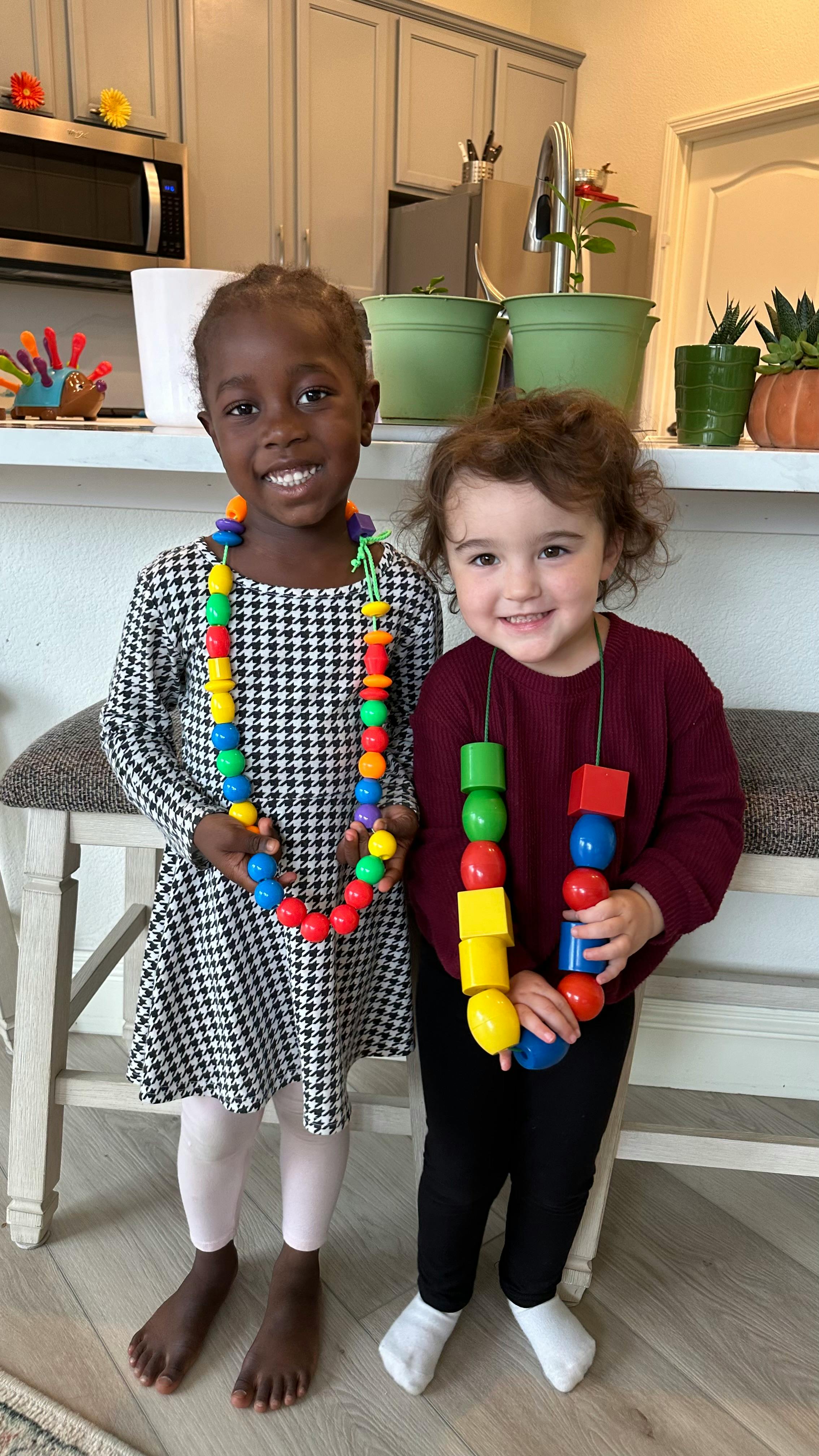 Two children wearing colorful beaded necklaces