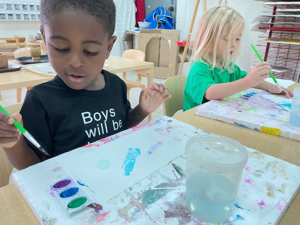 Two children painting at a table