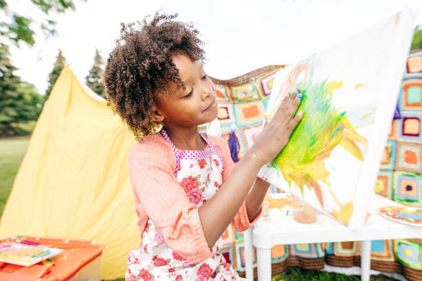 Child painting on a canvas outdoors