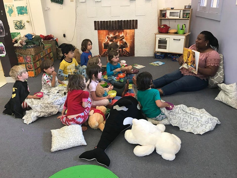 Adult reading a book to a group of children in a classroom