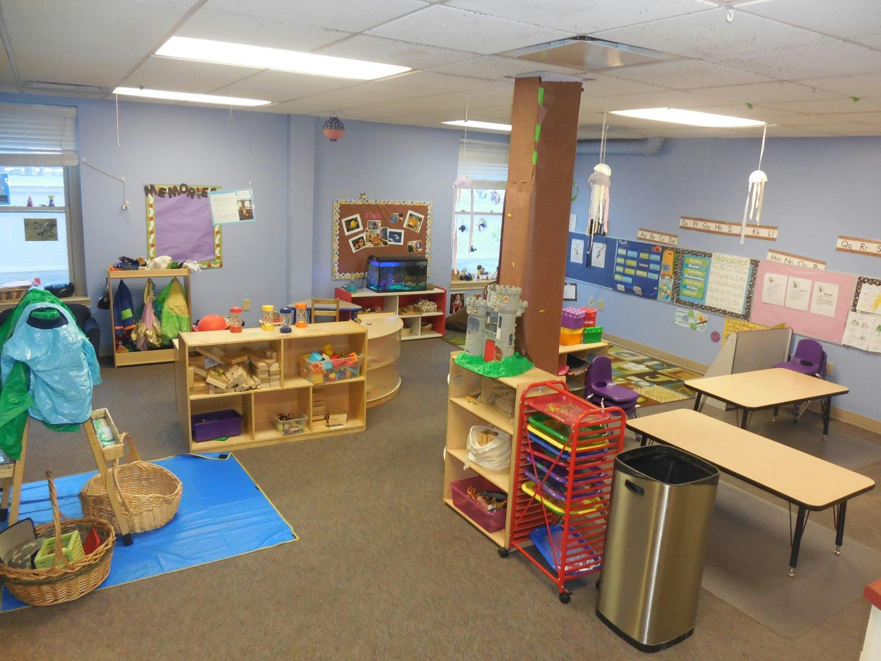 Classroom with small tables, shelves with toys, and bulletin boards