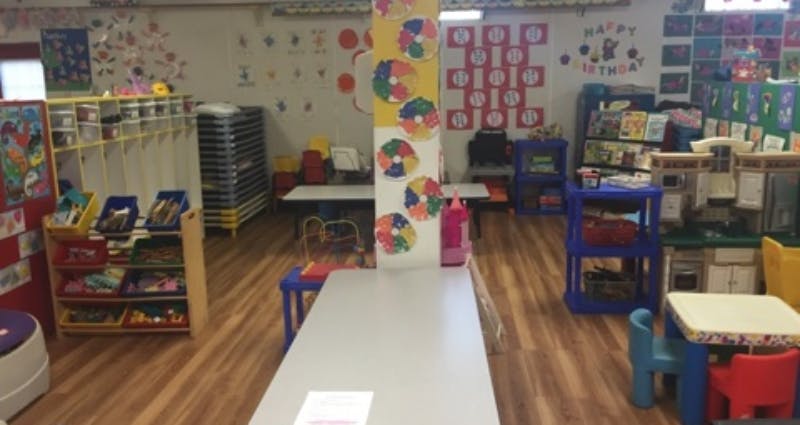 classroom with tables, chairs, and shelves with learning materials