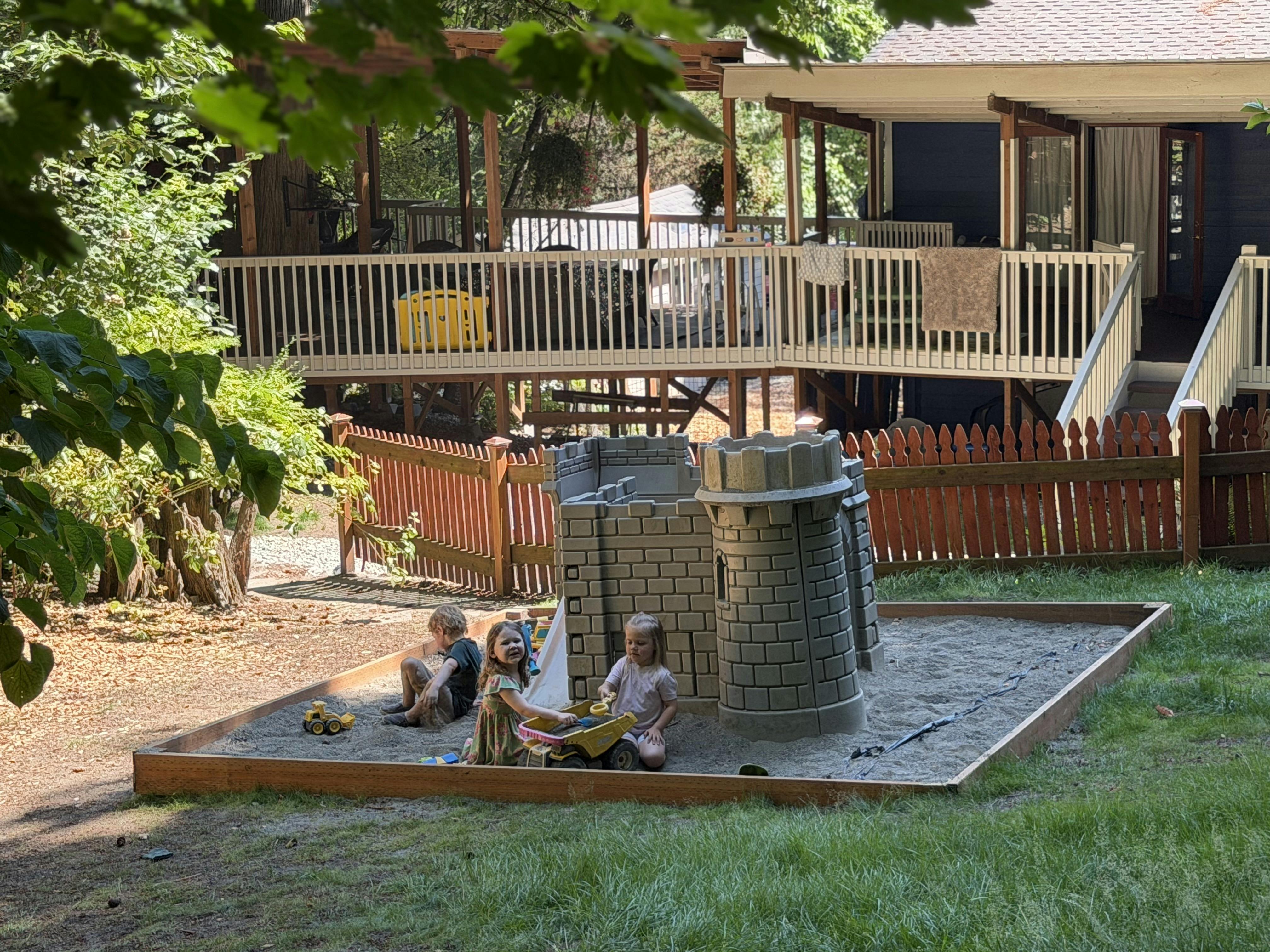 Children playing in a sandbox with a toy castle