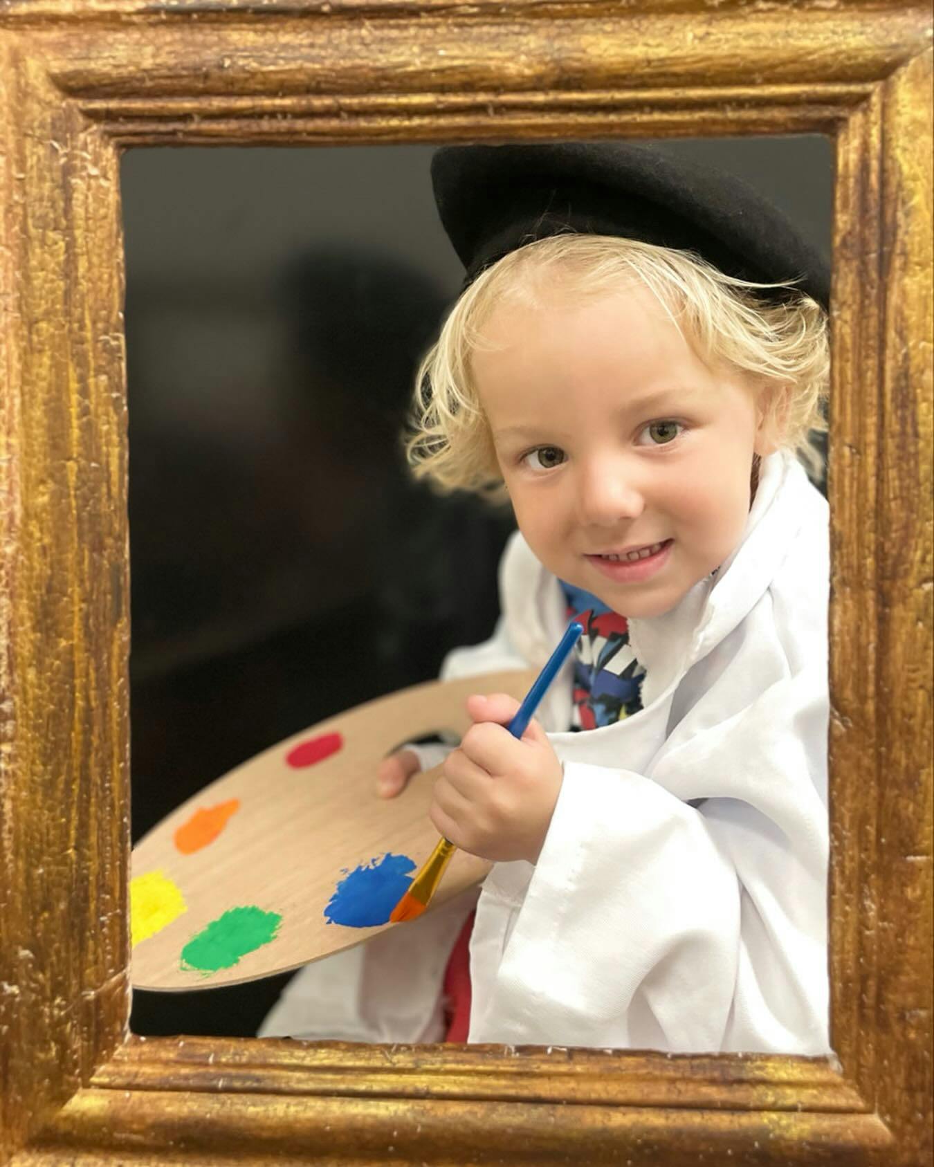 Child in beret and smock holding a paint palette and brush