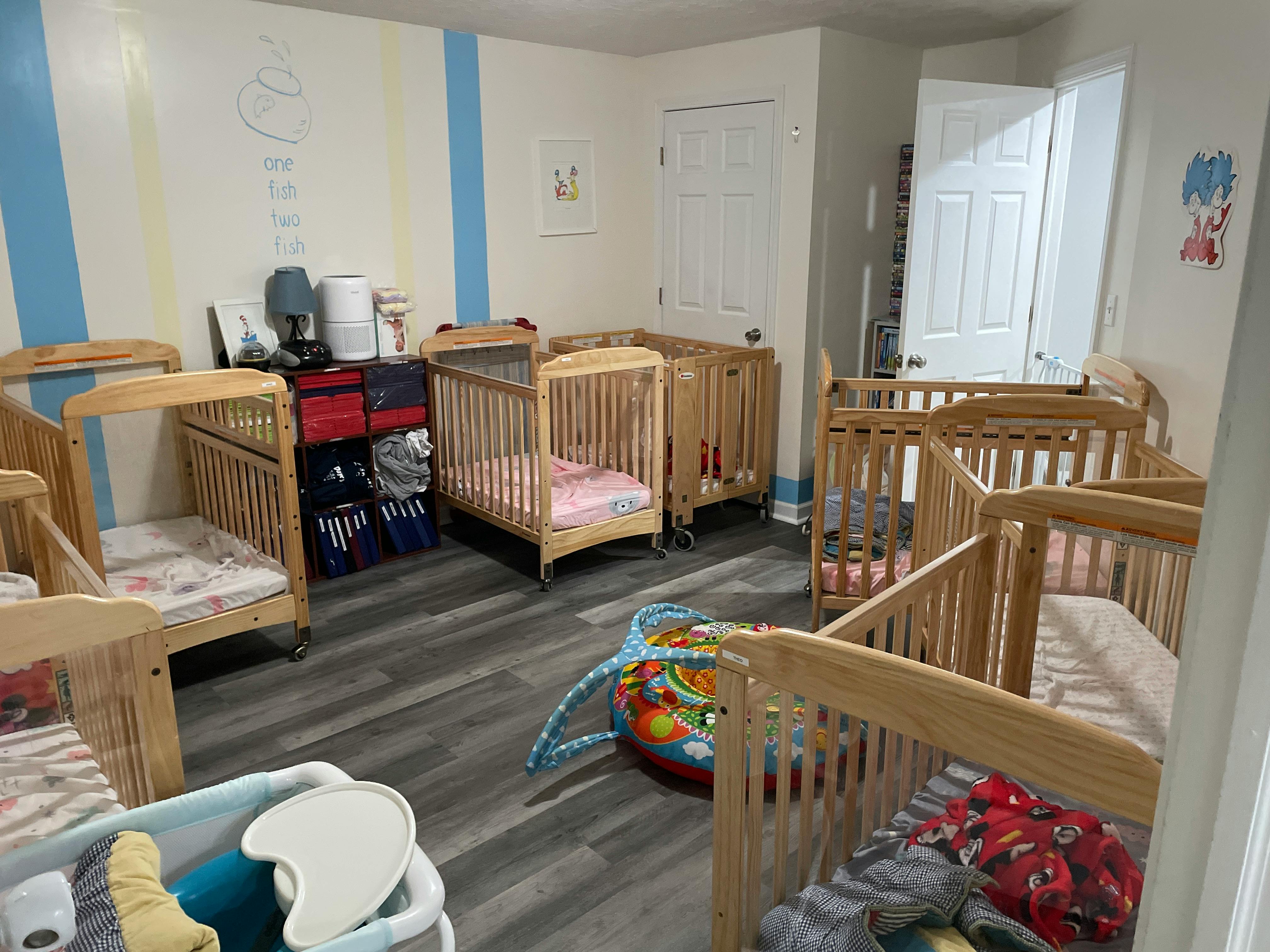 Multiple wooden cribs in a room with a dark wood floor