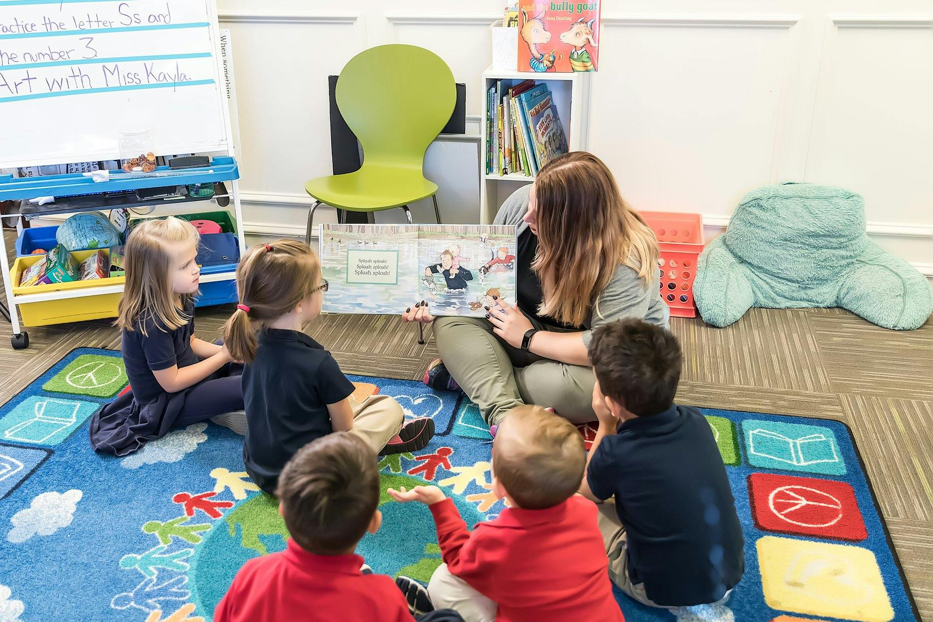 Adult reading a book to several children in a classroom