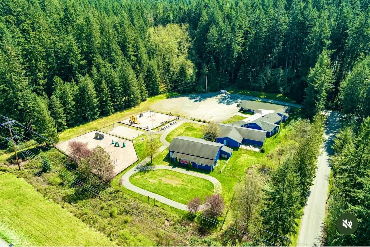 Aerial view of a blue building with a playground surrounded by a forest