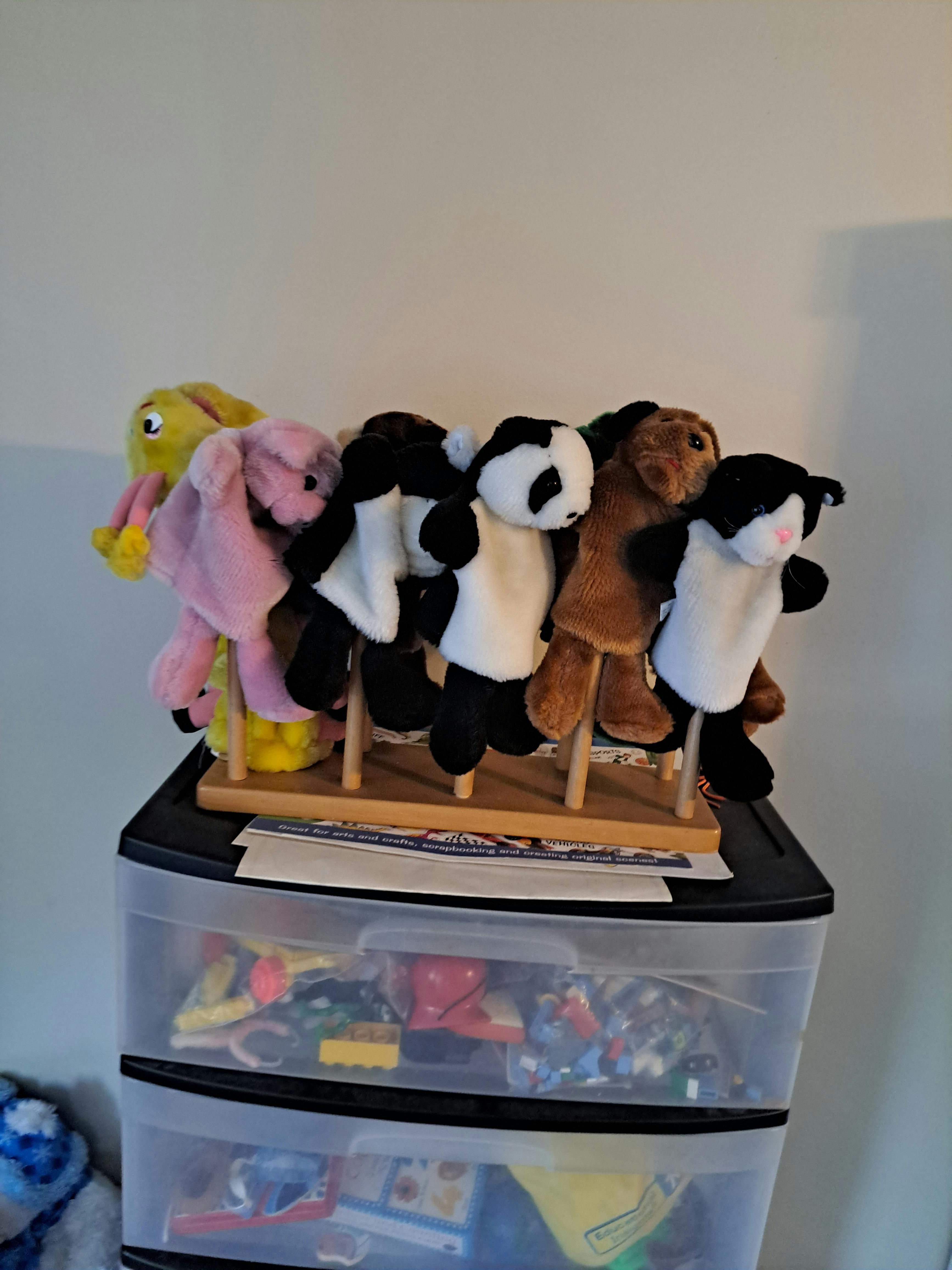 Multiple animal hand puppets on a wooden stand
