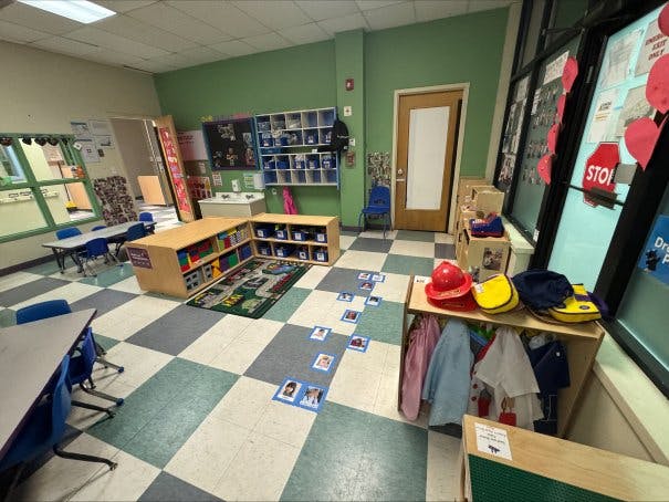 Empty classroom with small tables and chairs, storage units, and a checkered floor