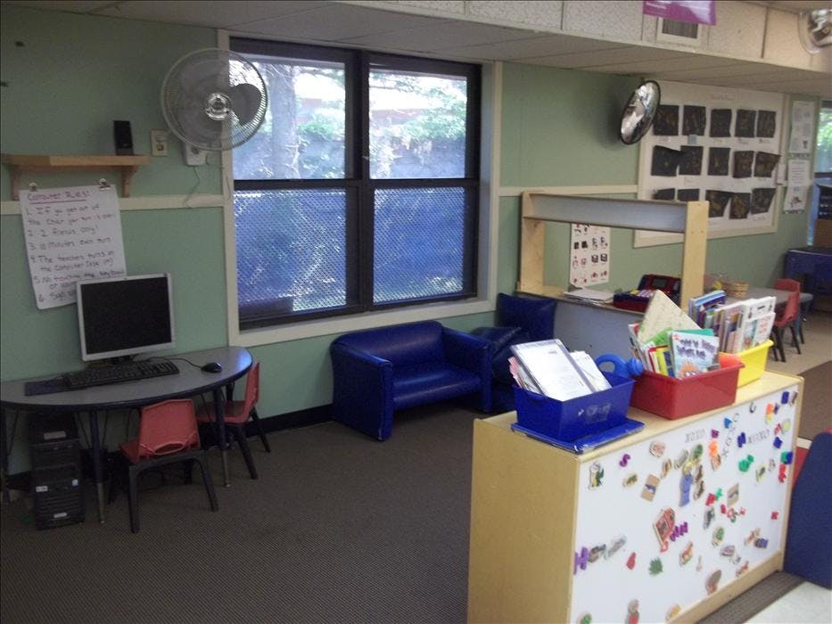 Classroom computer station with a desk, monitor, and keyboard, next to a window