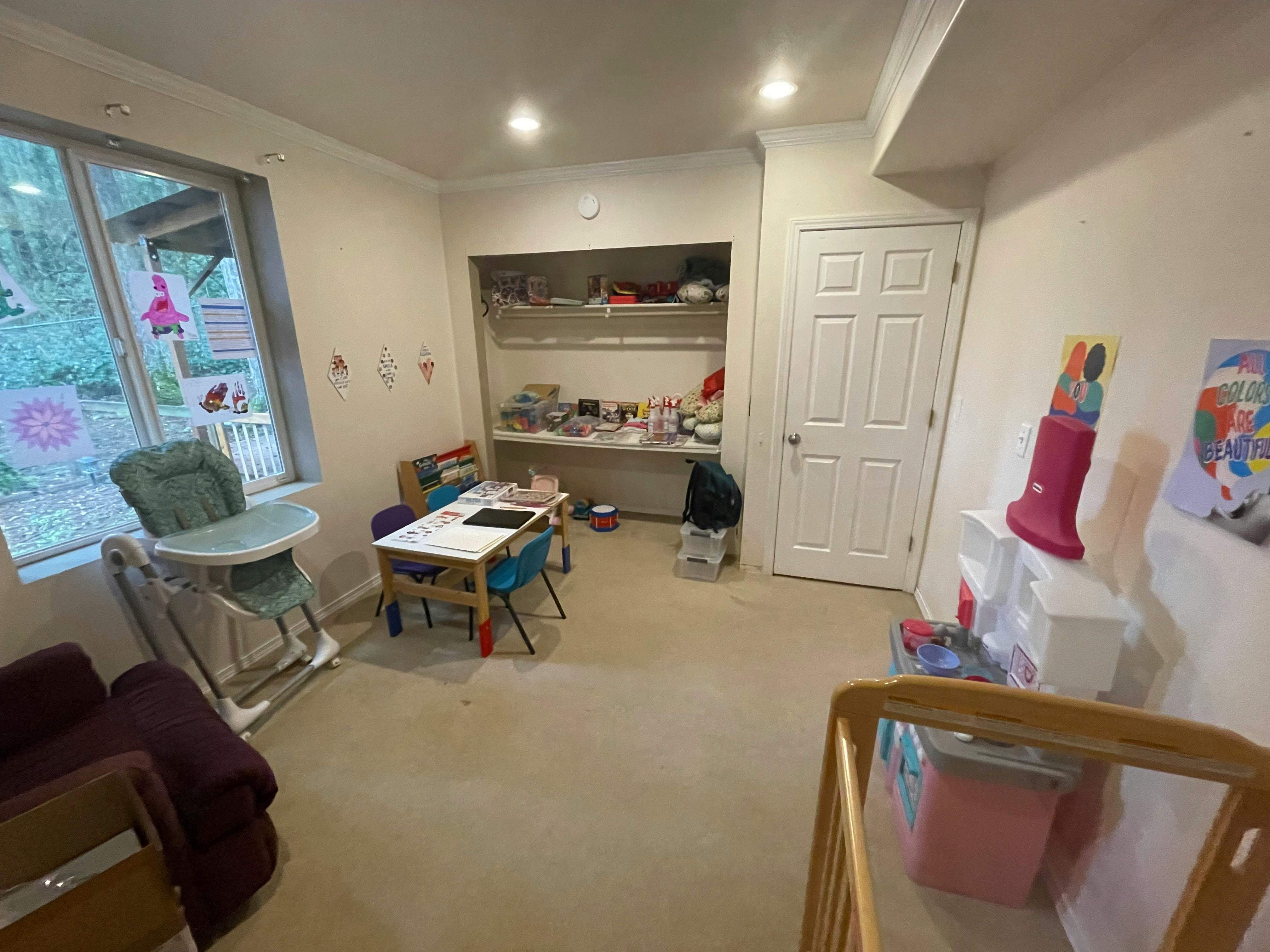 Playroom with a small table and chairs, high chair, and shelves with shelves