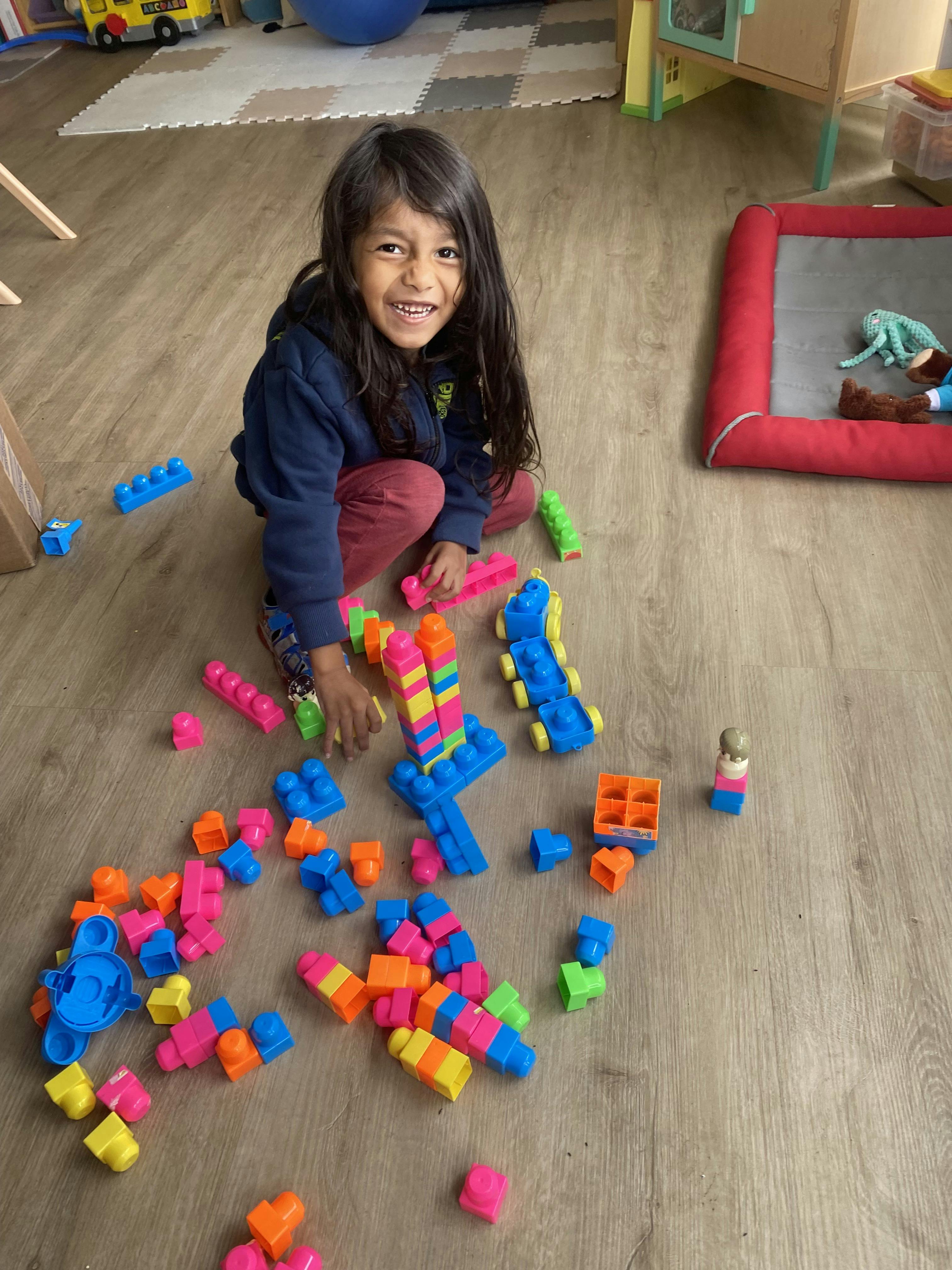 Child kneeling on the floor, playing with colorful building blocks