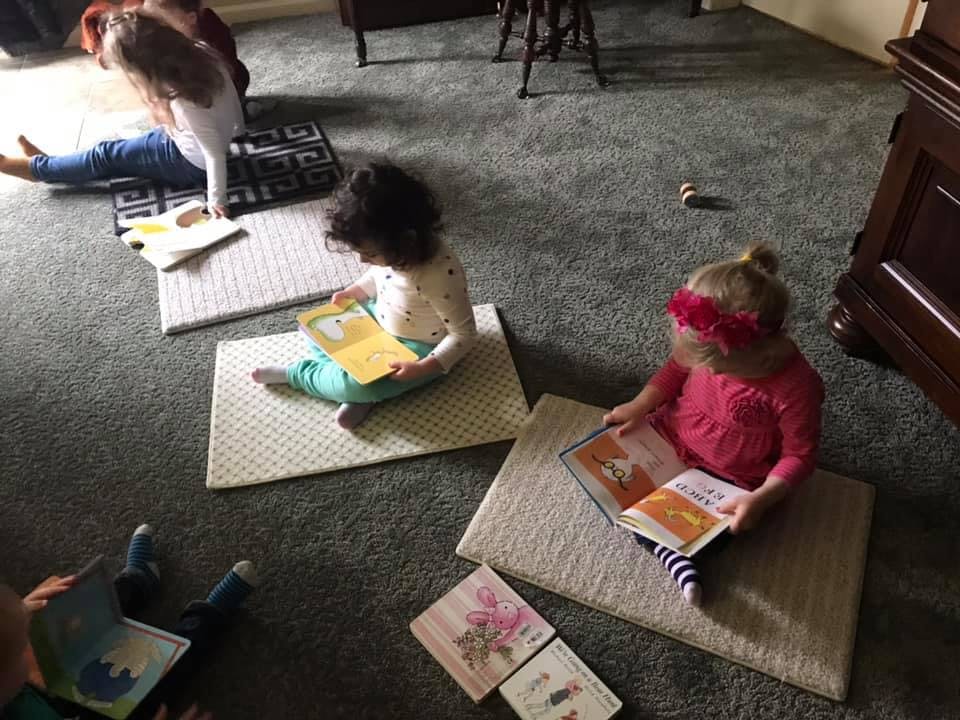 Children sitting on mats reading books
