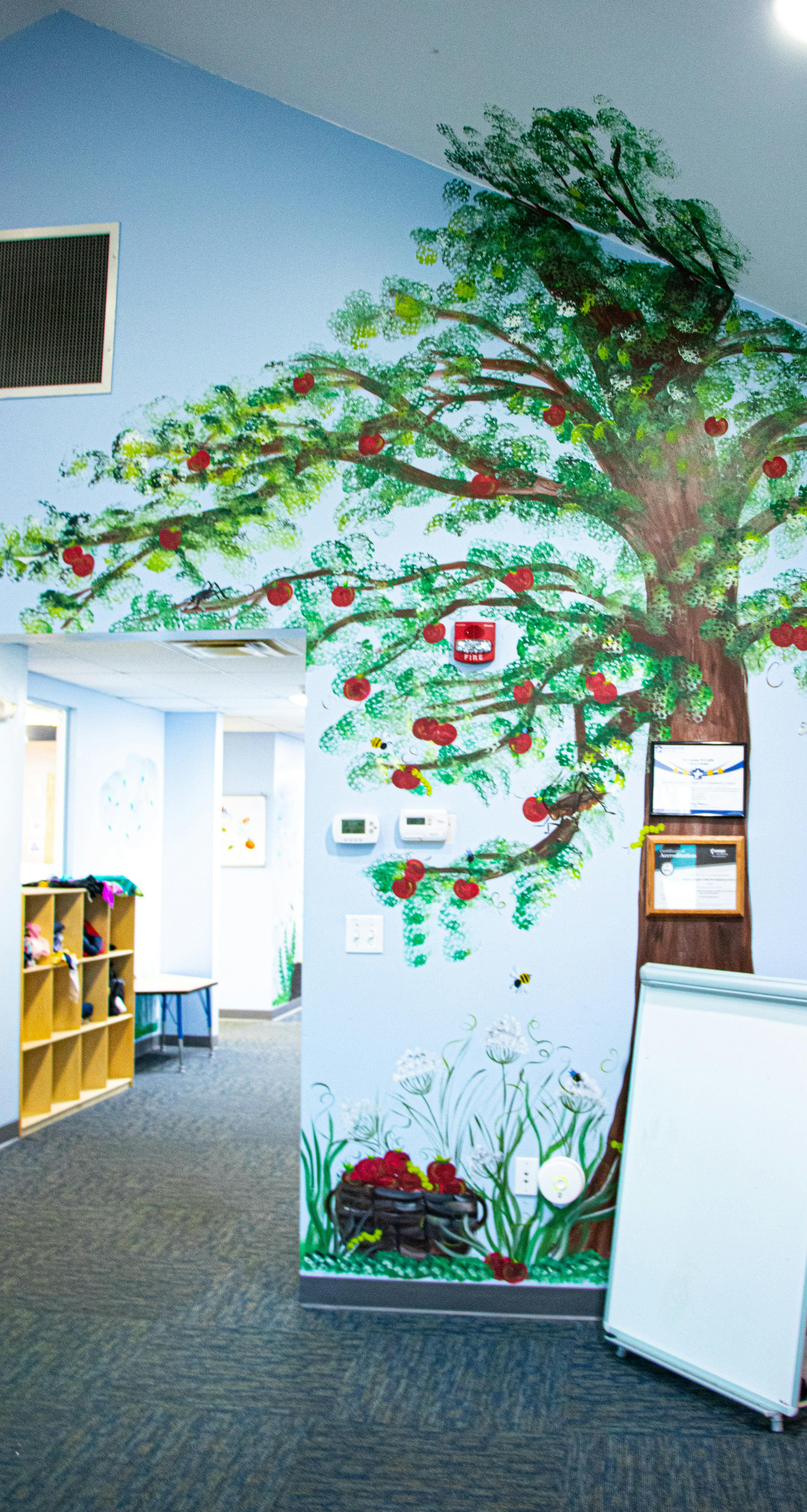 Wall mural of a tree with red apples and green leaves