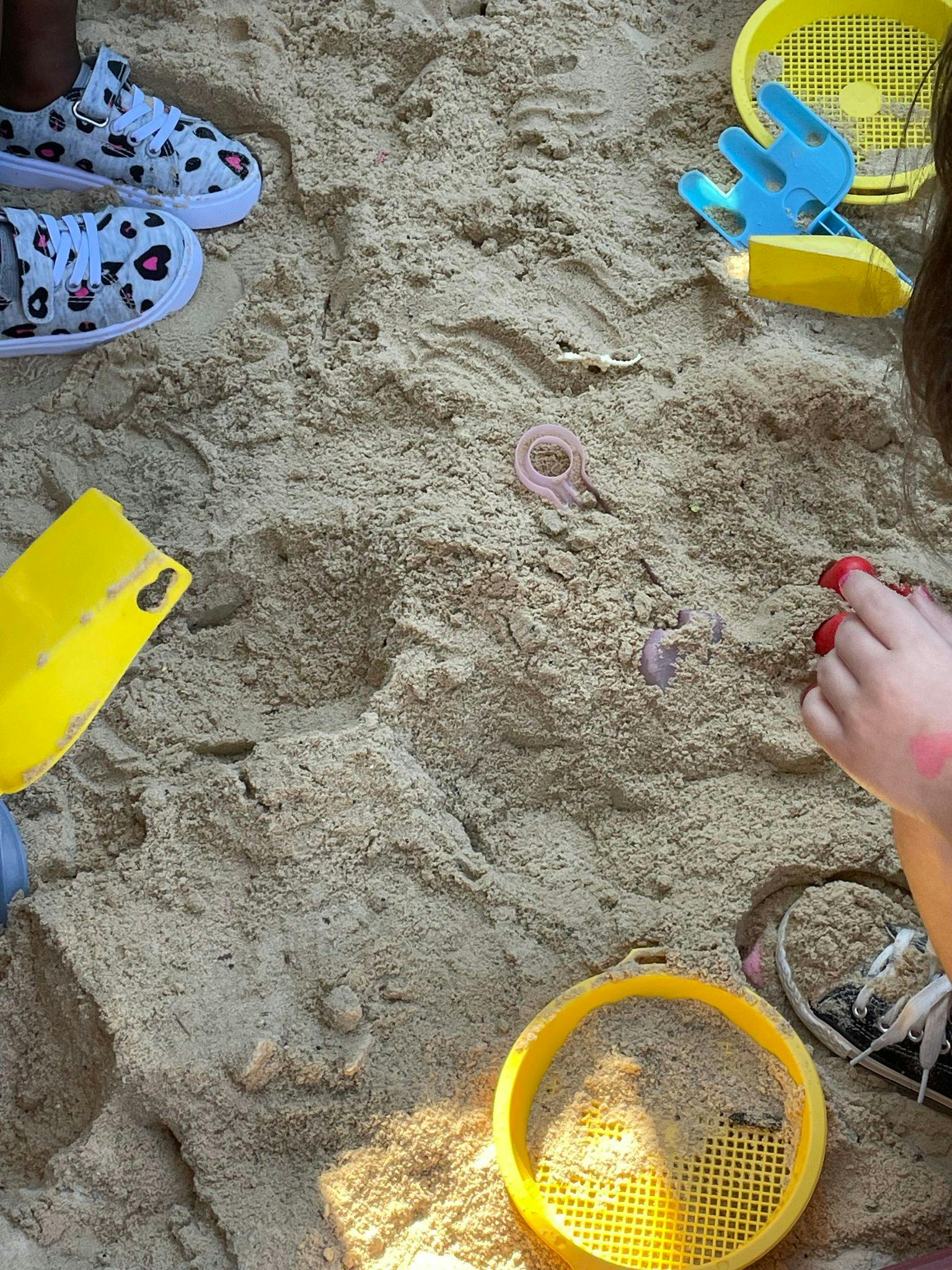 Feet of people and sand toys in sand