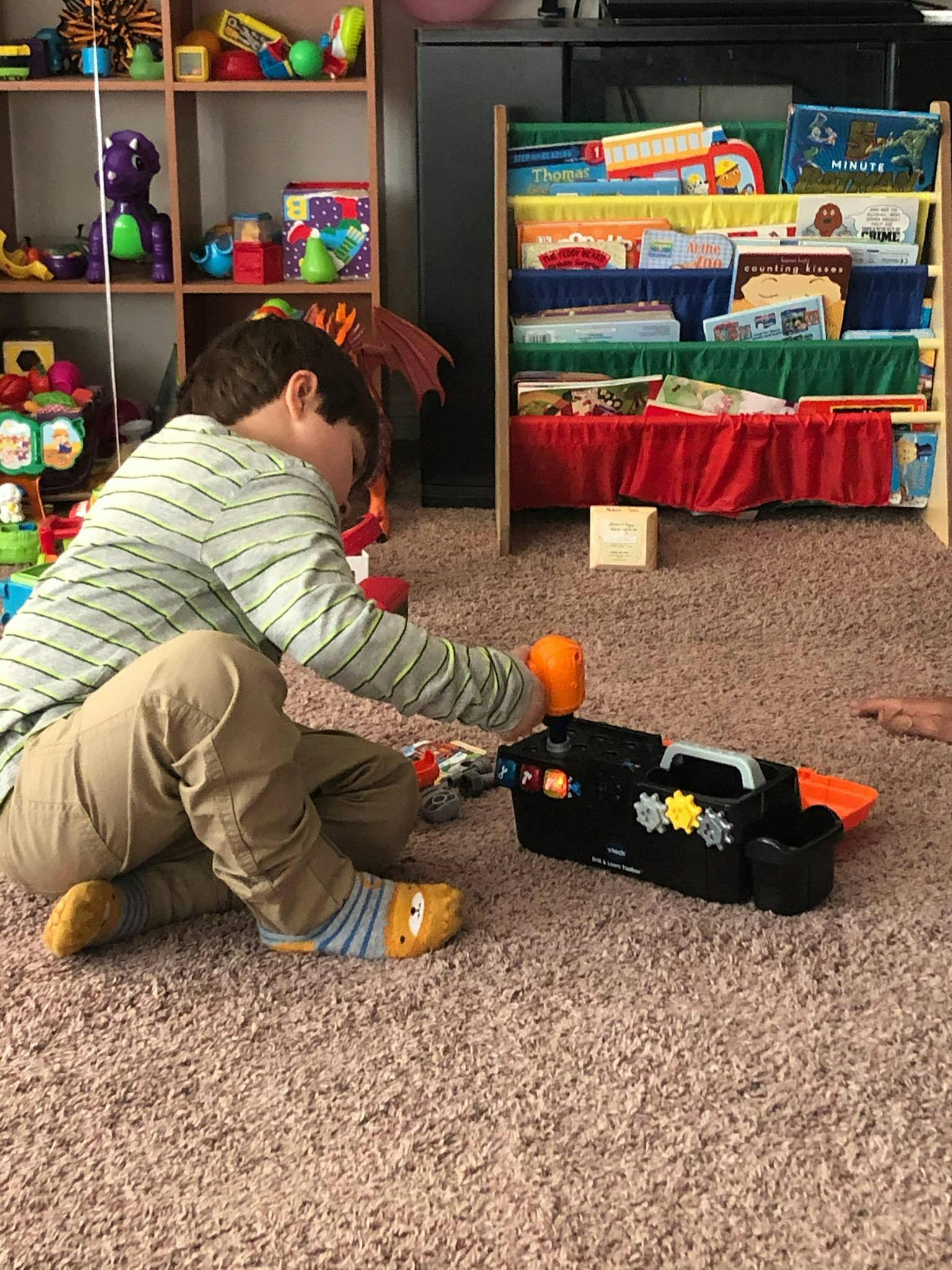 Child playing with a toy toolbox on the floor