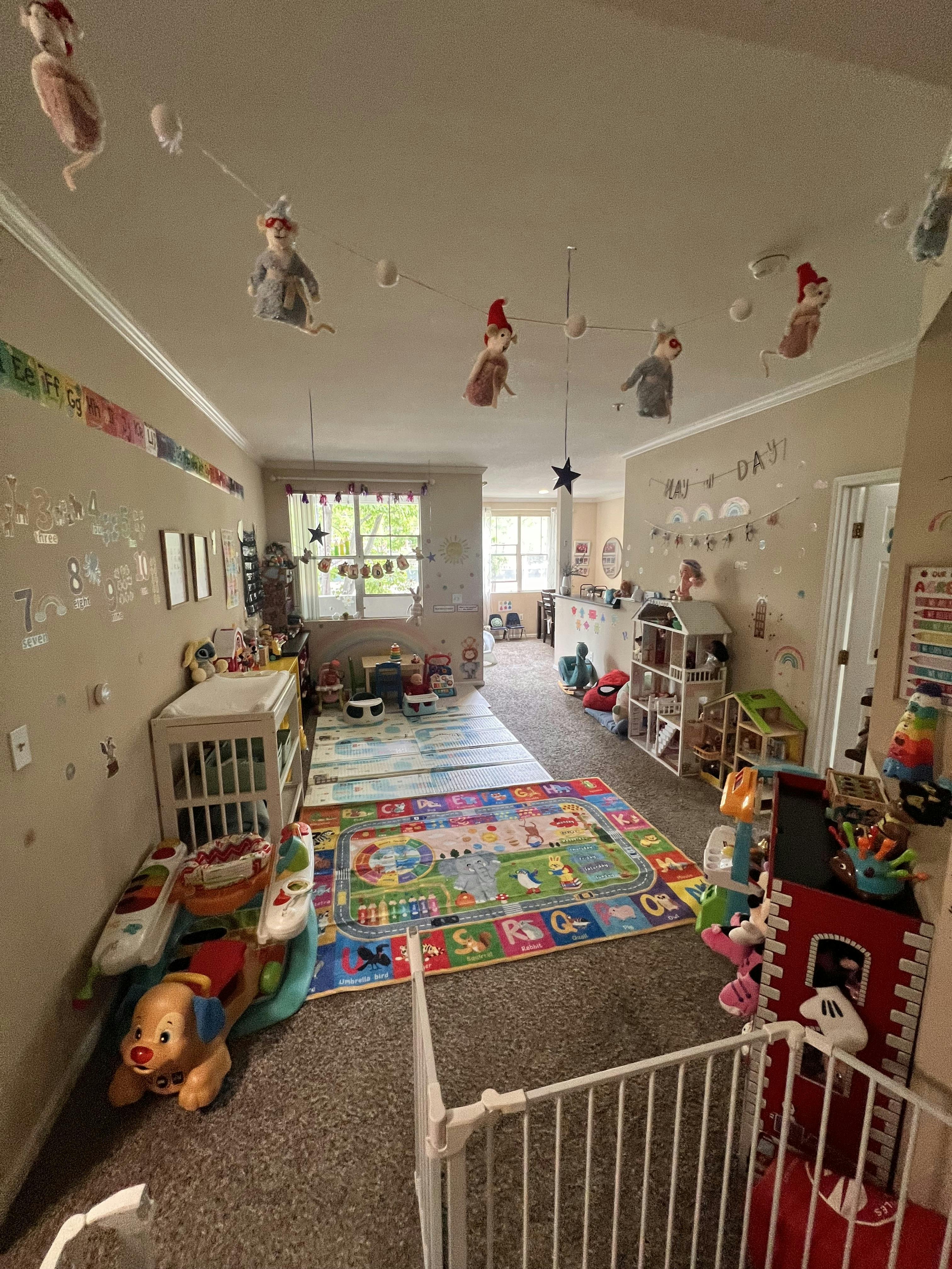 A playroom filled with toys, playmats, a crib, and various wall decorations