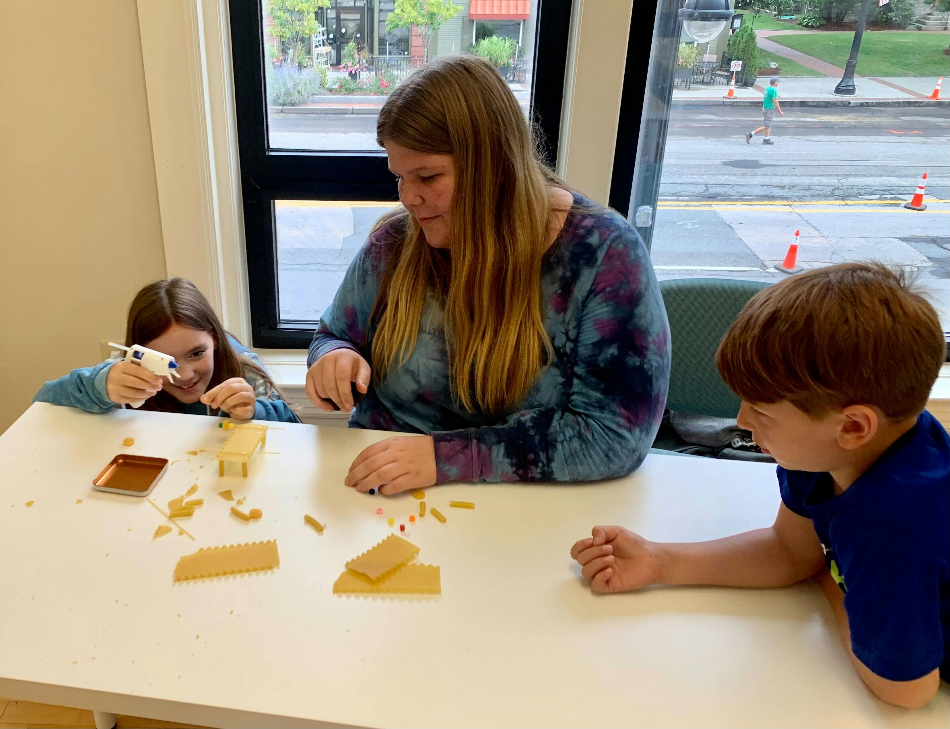 Adult and two children at a table with craft supplies
