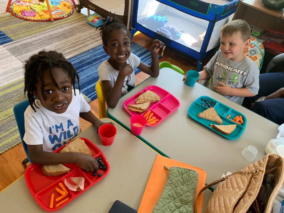 Three children eating lunch at a table