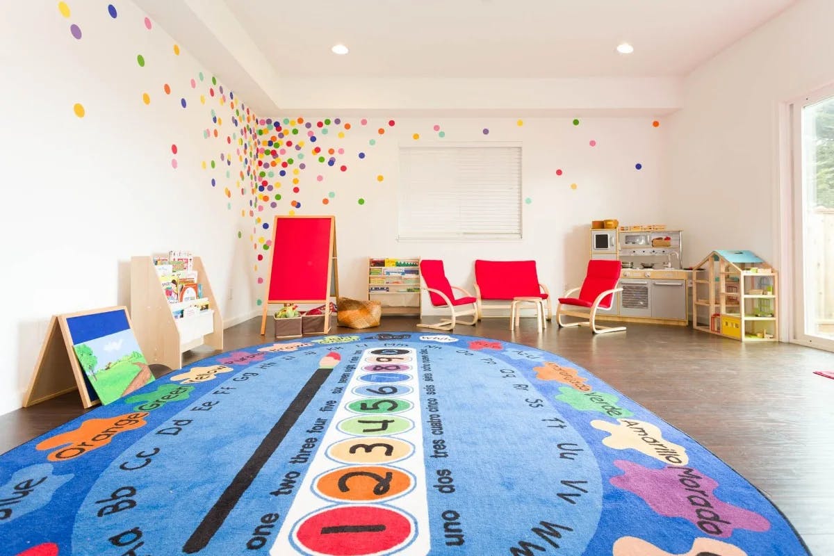 Playroom with a blue rug, red chairs, and colorful wall decals