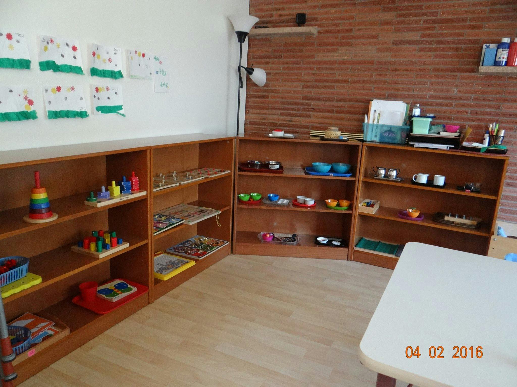 Classroom with wooden shelves holding various learning materials and toys