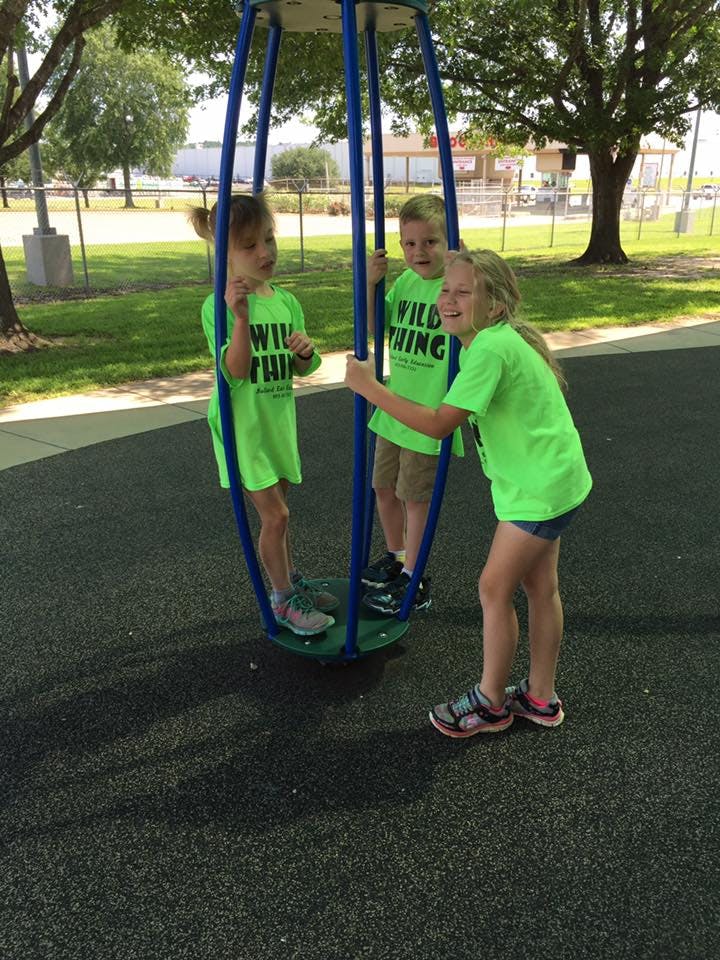 Three children playing on a playground spinner