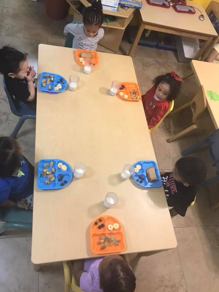Children sitting at a table with plates of snacks and drinks