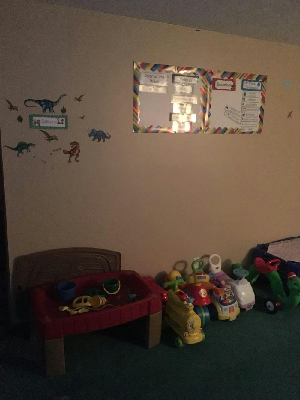 Wall with dinosaur decals, two framed papers, and toys on the floor