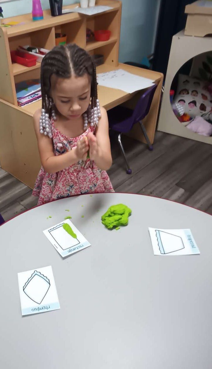 Child playing with green playdough at a table