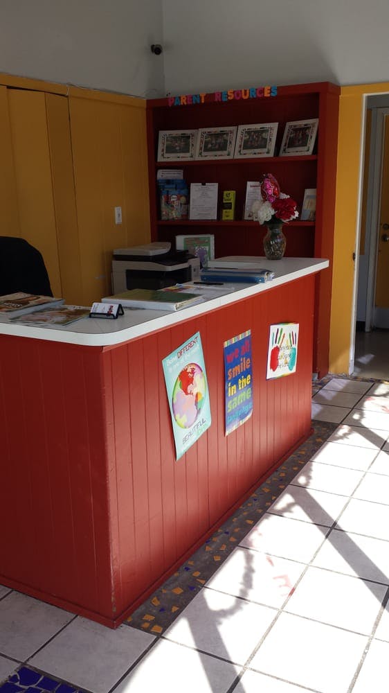 Red reception desk with posters and a bookshelf in a room with yellow walls