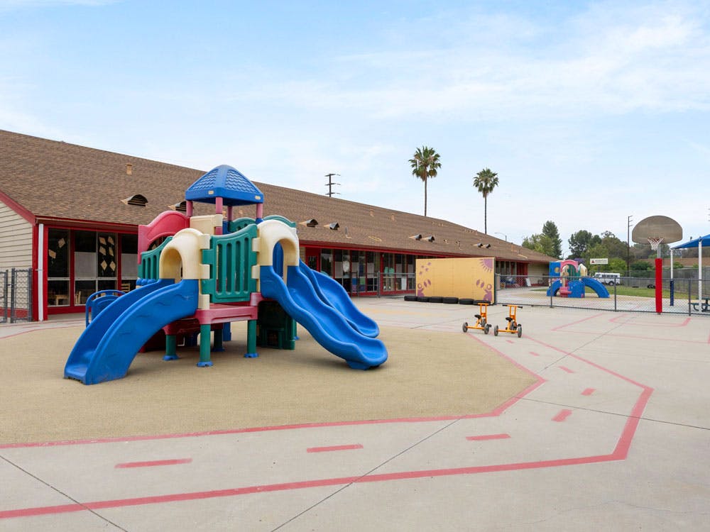 Playground with blue slides and brown building in the background