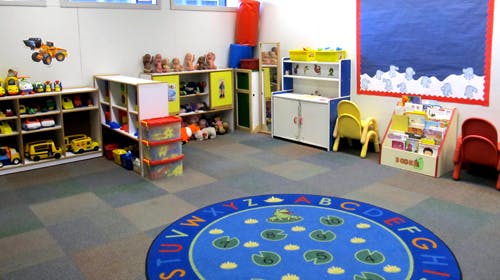 Playroom with toys, shelves, and a blue alphabet rug