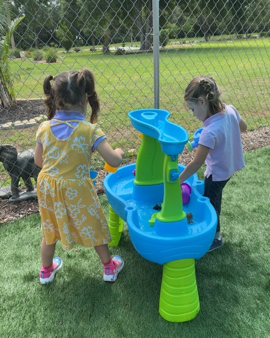 Two children playing with a water table outdoors