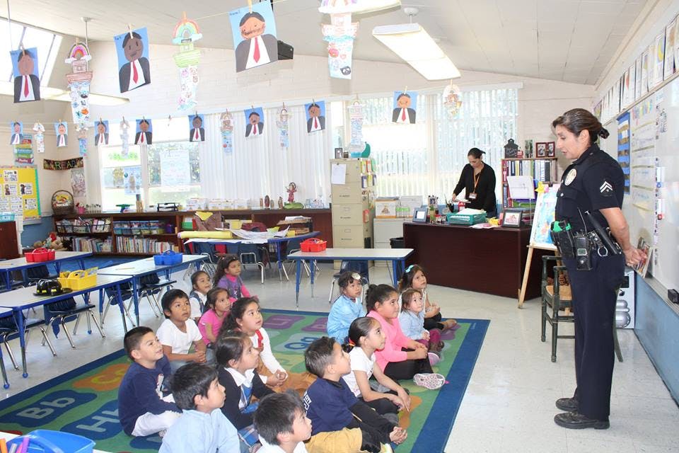 Police officer speaking to children sitting on a rug in a classroom
