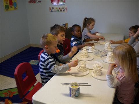 Children sitting at a table with small white cakes