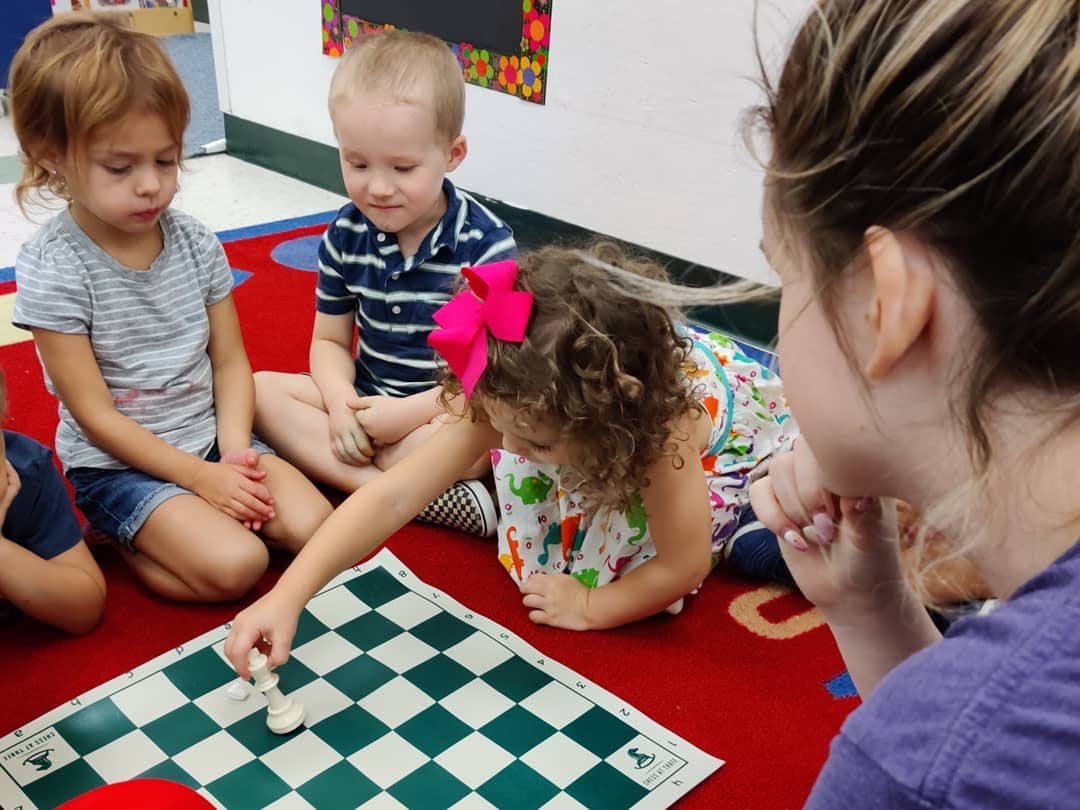 Children and an adult playing a board game on the floor