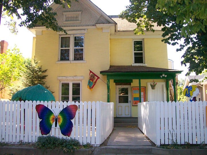 Yellow house with a white picket fence and a colorful butterfly decoration