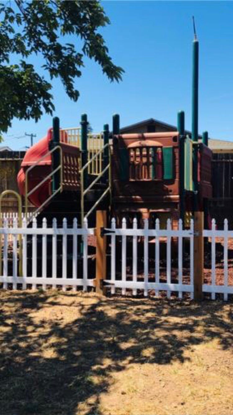 Playground structure with a white picket fence in front