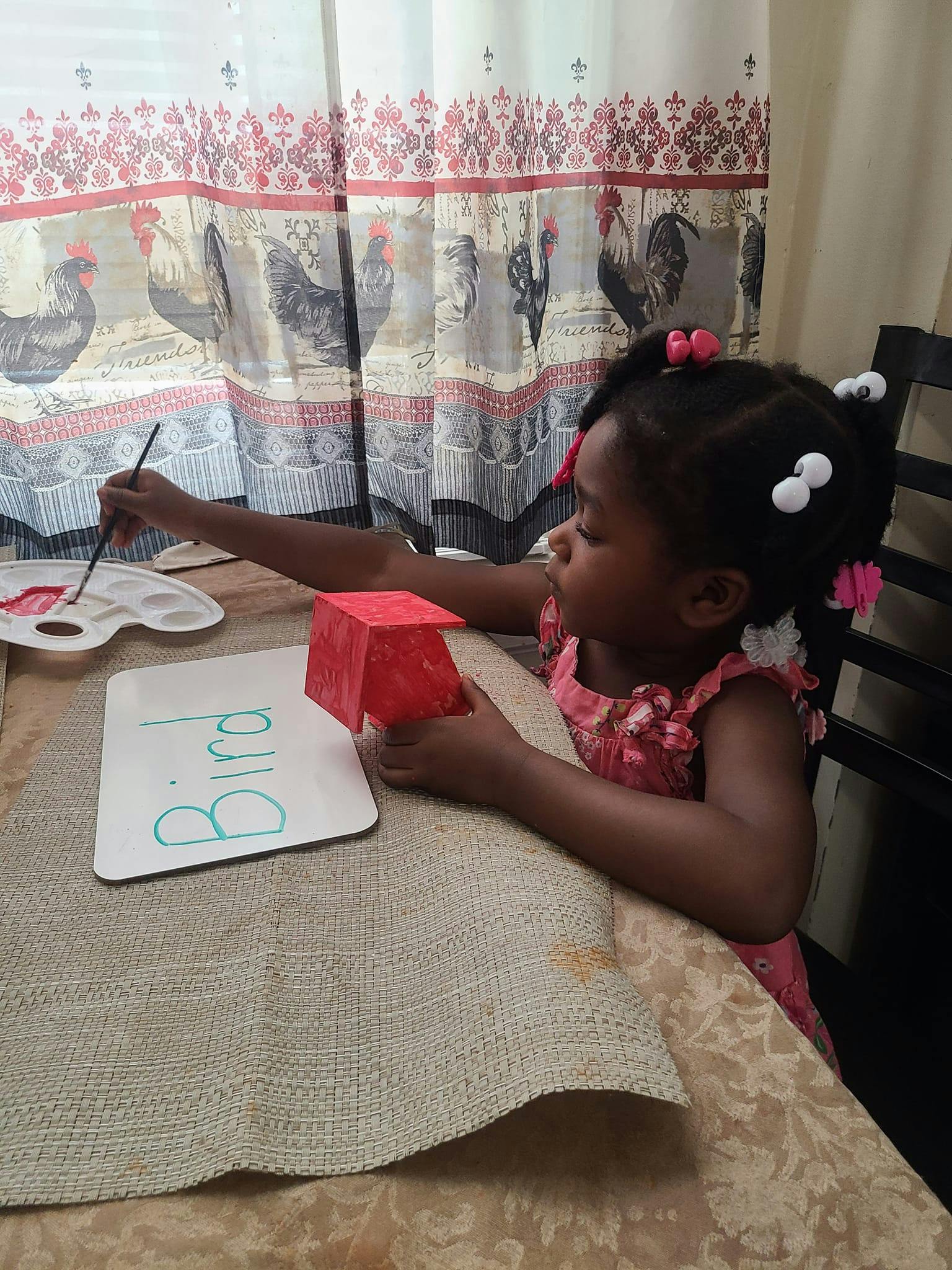 Child painting a red object at a table